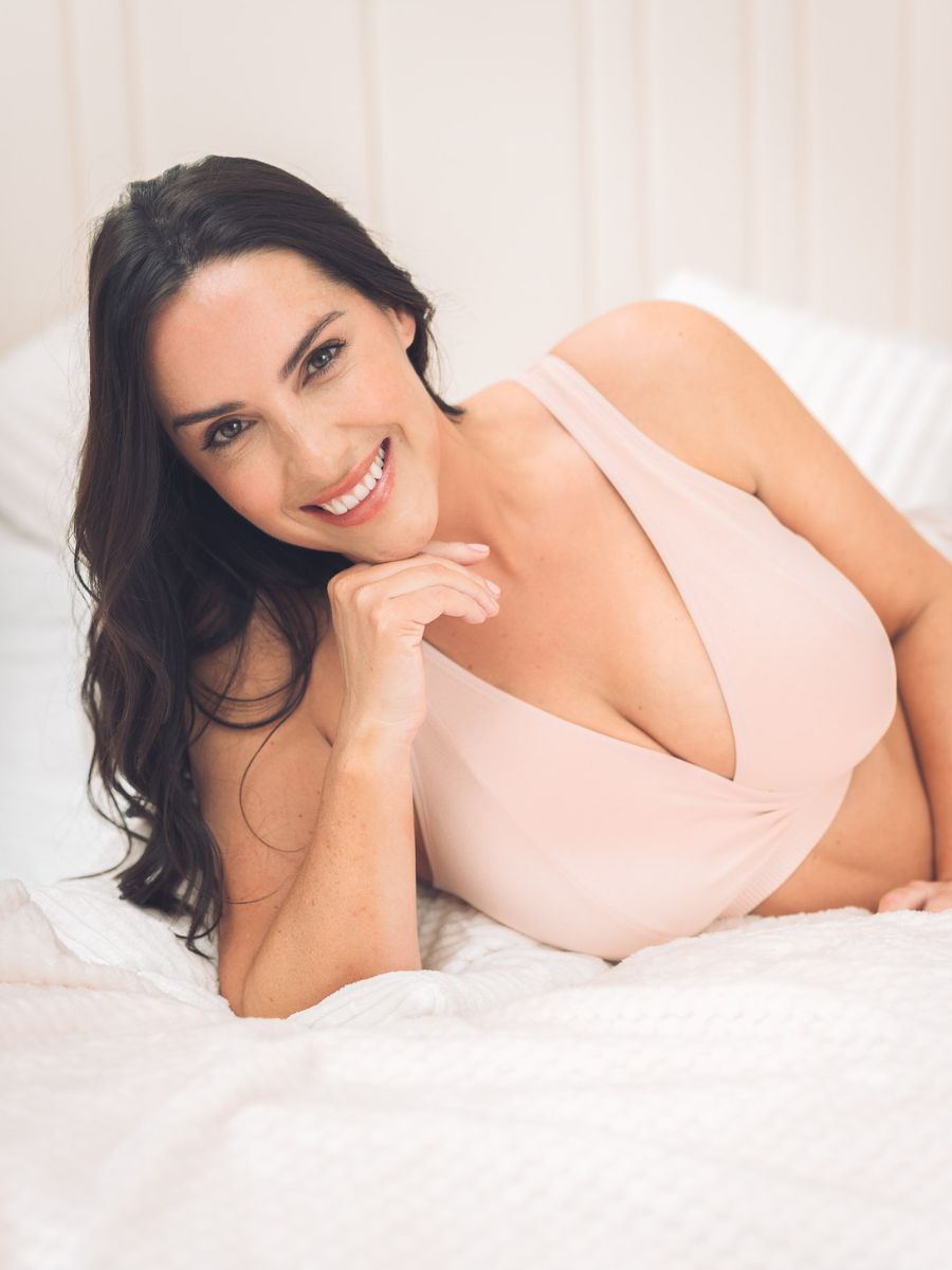 women laying on a bed in a soft blush bra
