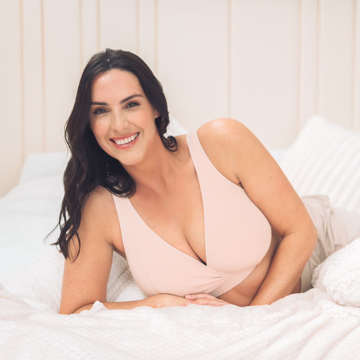 women laying on a bed in a soft blush bra